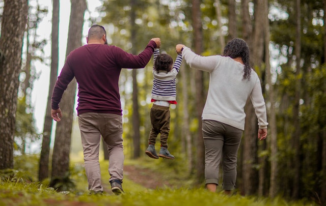 A man, woman and child walking through the woods.
